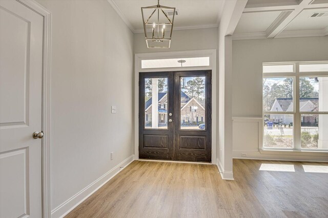 entrance foyer featuring a chandelier, coffered ceiling, light hardwood / wood-style floors, crown molding, and french doors