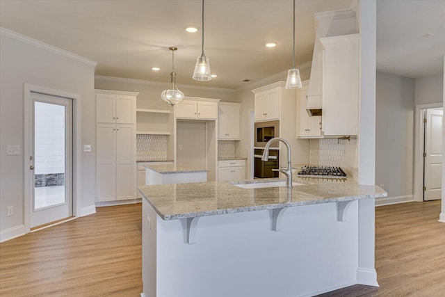 kitchen with light stone counters, a breakfast bar, sink, and white cabinets