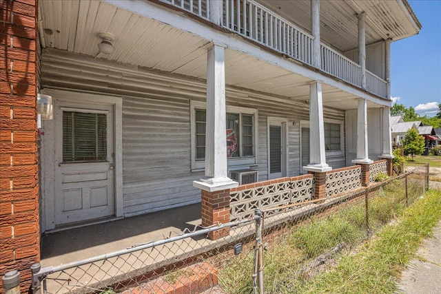 view of exterior entry featuring a porch and a balcony