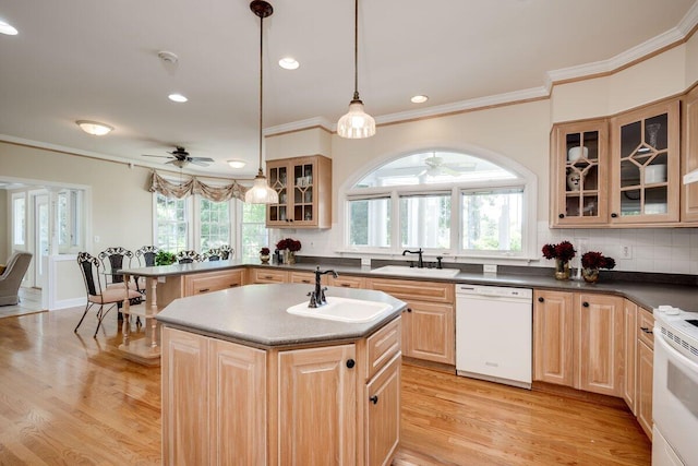 kitchen featuring white appliances, sink, a kitchen island with sink, and hanging light fixtures