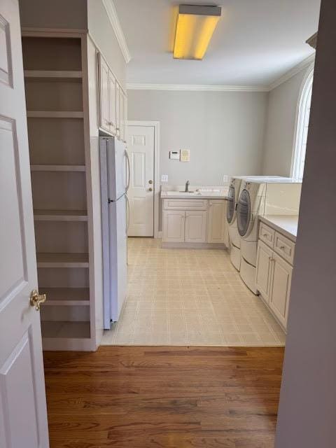 laundry room with cabinets, crown molding, light wood-type flooring, and independent washer and dryer