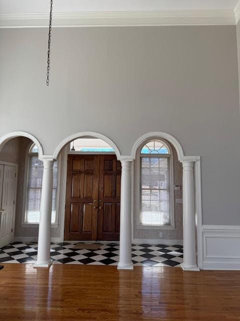 entryway featuring decorative columns, ornamental molding, a high ceiling, and dark hardwood / wood-style flooring