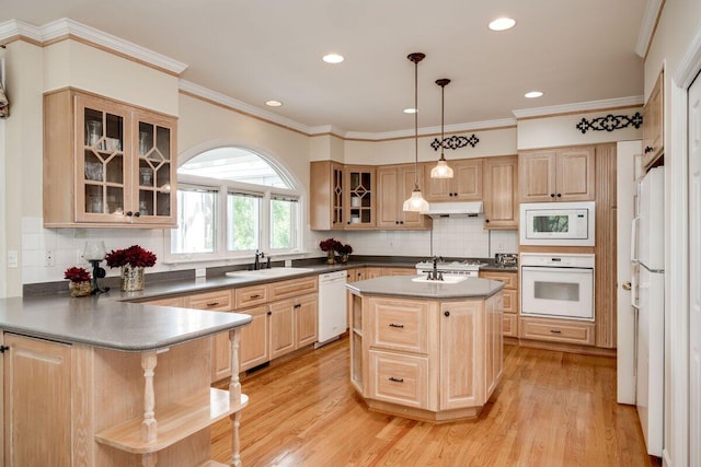 kitchen with pendant lighting, sink, white appliances, a kitchen island, and light wood-type flooring