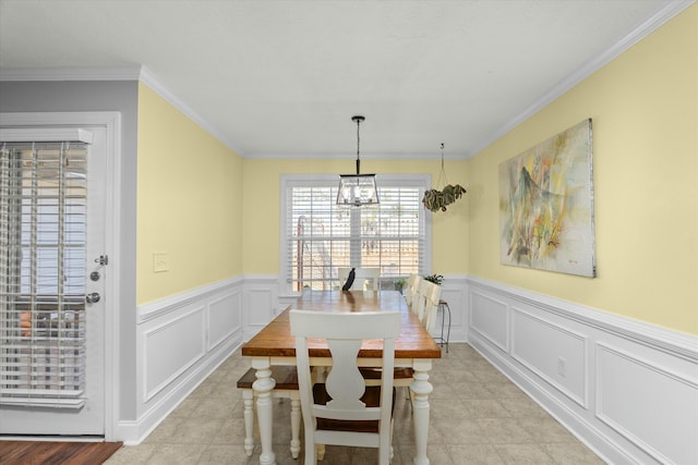 dining area featuring light tile patterned flooring, ornamental molding, wainscoting, a decorative wall, and a chandelier