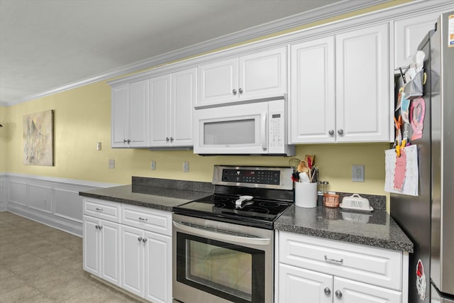 kitchen featuring a wainscoted wall, ornamental molding, appliances with stainless steel finishes, a decorative wall, and white cabinets