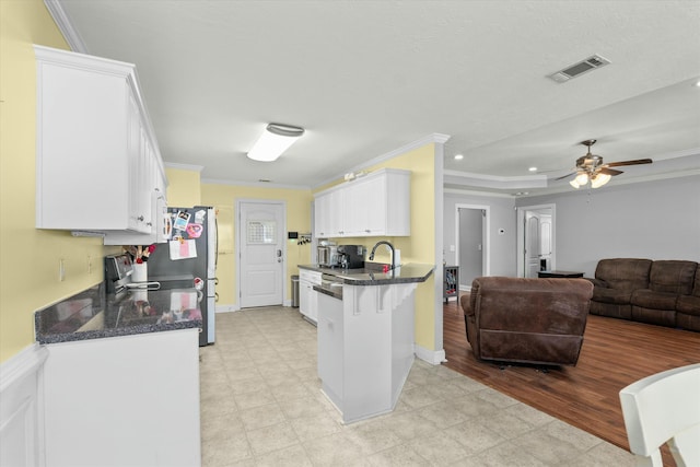 kitchen with visible vents, open floor plan, ornamental molding, and white cabinetry