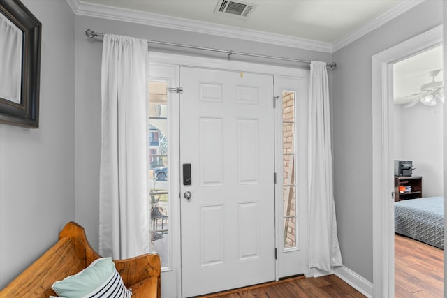 foyer entrance with visible vents, ornamental molding, dark wood finished floors, baseboards, and ceiling fan