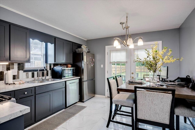 kitchen with stainless steel appliances, a sink, a chandelier, light countertops, and light marble finish flooring