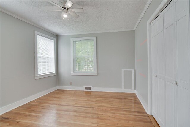 unfurnished bedroom with ceiling fan, light hardwood / wood-style flooring, a textured ceiling, and ornamental molding