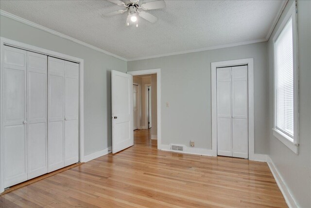 unfurnished bedroom featuring multiple windows, ceiling fan, and ornamental molding