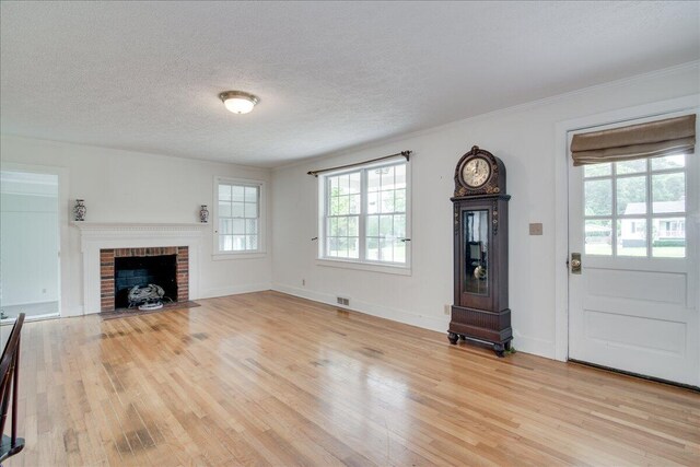 unfurnished living room with a fireplace, light hardwood / wood-style flooring, and a textured ceiling