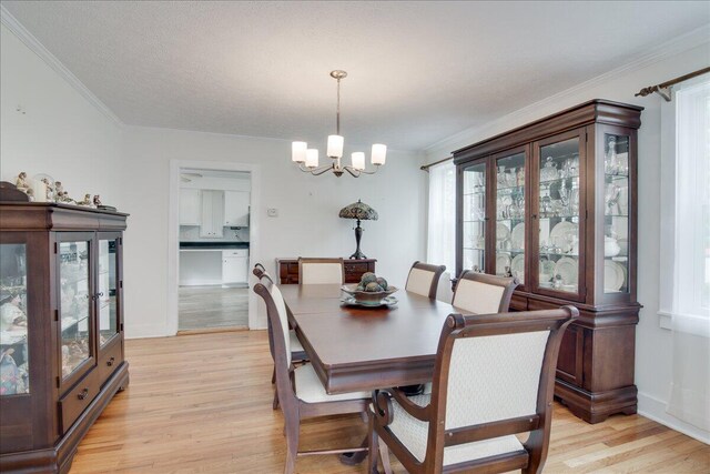 dining area featuring light hardwood / wood-style flooring, ornamental molding, and a notable chandelier