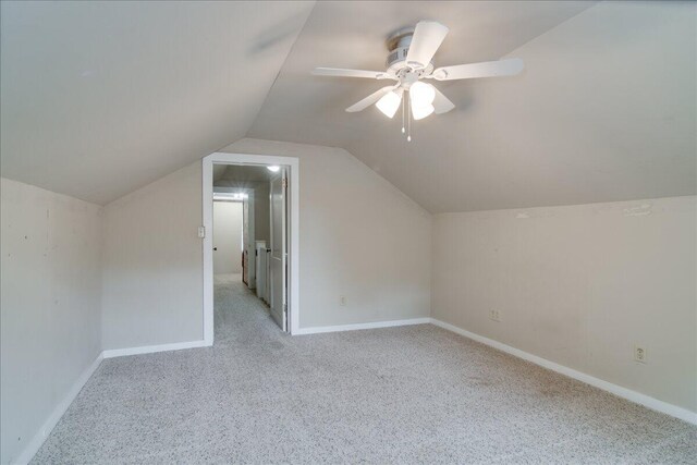 additional living space with ceiling fan, light colored carpet, and vaulted ceiling