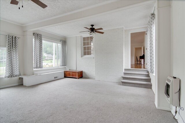 carpeted empty room with a textured ceiling, heating unit, ceiling fan, and ornamental molding