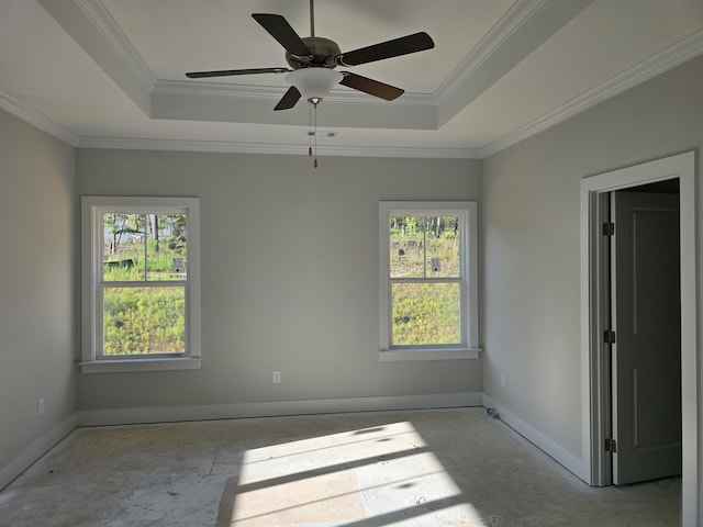 empty room with ceiling fan, a wealth of natural light, and a tray ceiling