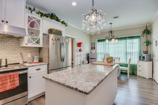 kitchen with stainless steel appliances, under cabinet range hood, visible vents, white cabinetry, and ornamental molding