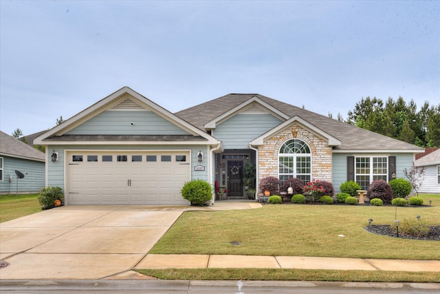 craftsman house featuring a front lawn, driveway, stone siding, and an attached garage