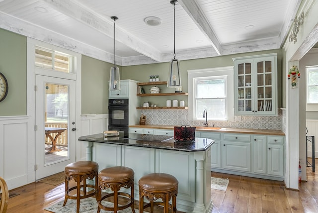 kitchen featuring a breakfast bar area, tasteful backsplash, a center island, and light wood-type flooring