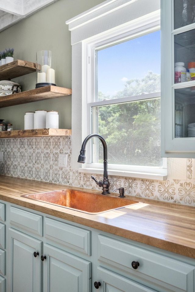 room details featuring backsplash, butcher block countertops, white cabinetry, and sink