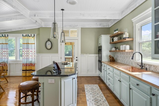 kitchen featuring a breakfast bar, sink, decorative light fixtures, a kitchen island, and butcher block counters