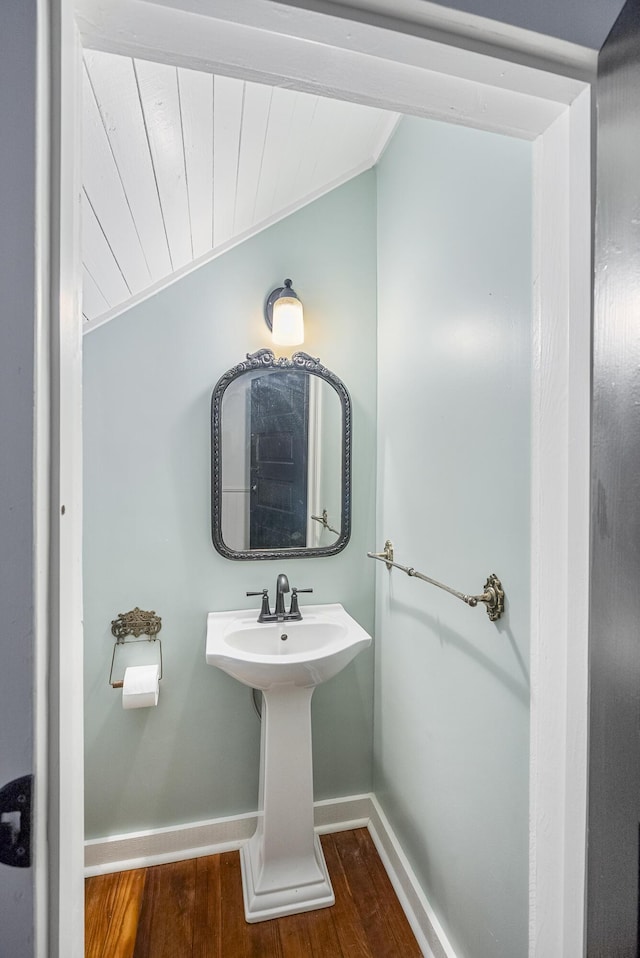 bathroom featuring hardwood / wood-style floors, ornamental molding, and lofted ceiling