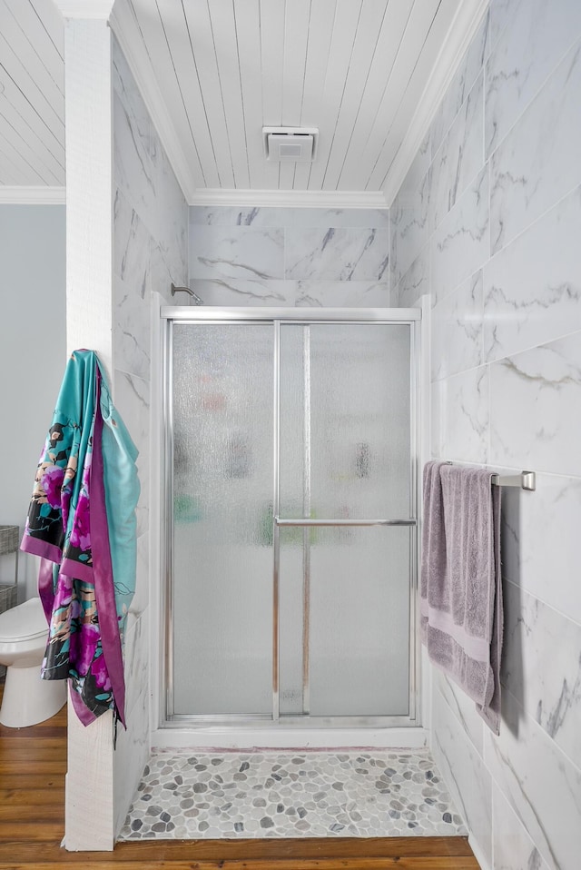 bathroom with crown molding, hardwood / wood-style floors, toilet, a shower with door, and tile walls