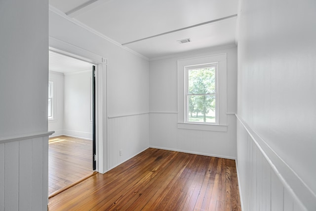 spare room with hardwood / wood-style floors and crown molding