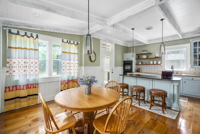 dining space featuring beamed ceiling and light hardwood / wood-style flooring