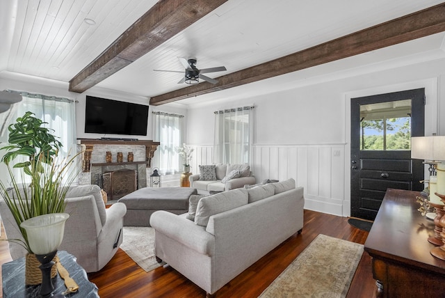 living room featuring ceiling fan, beam ceiling, a fireplace, dark hardwood / wood-style floors, and plenty of natural light