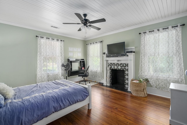 bedroom with ceiling fan, ornamental molding, dark wood-type flooring, and a tile fireplace