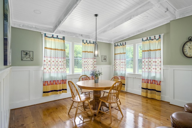 dining room with lofted ceiling with beams and light hardwood / wood-style flooring