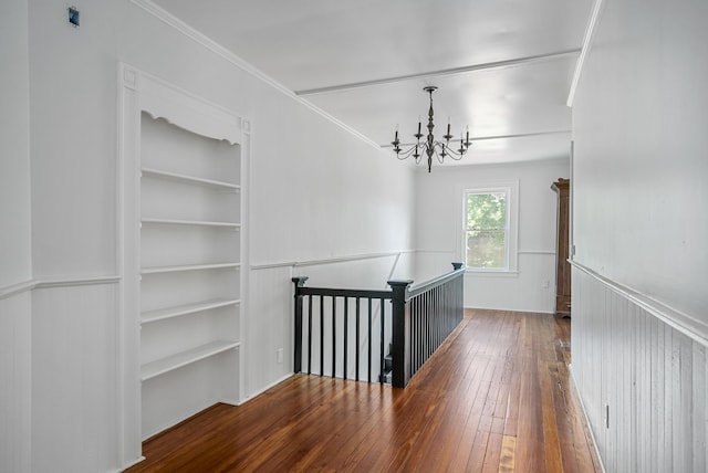 hallway with dark hardwood / wood-style flooring, crown molding, and an inviting chandelier