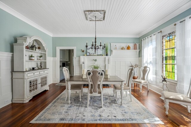 dining space with crown molding, built in features, dark wood-type flooring, and a chandelier