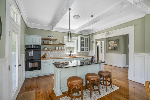 kitchen with sink, double oven, light hardwood / wood-style floors, decorative backsplash, and white cabinets