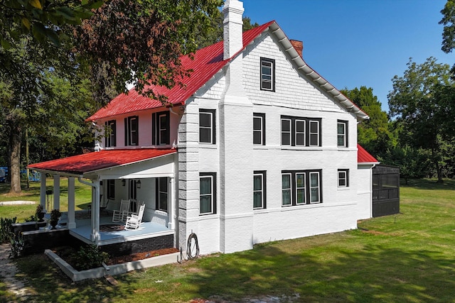 back of house featuring a lawn and a porch