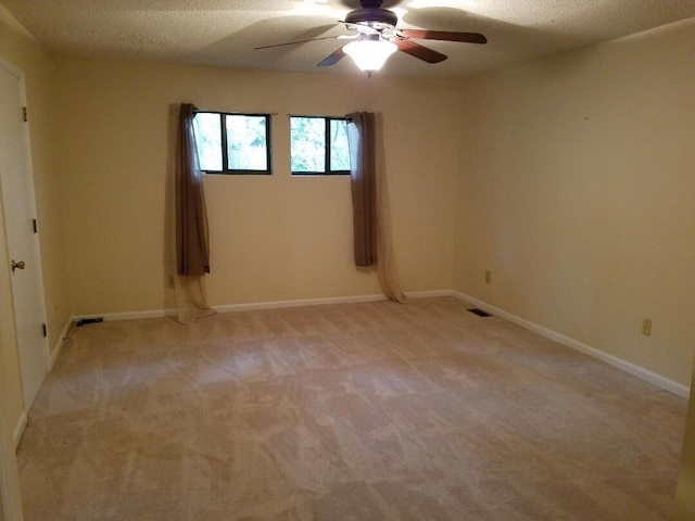 empty room featuring a textured ceiling, light colored carpet, and ceiling fan