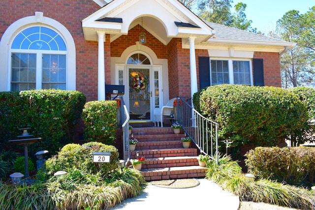 property entrance with brick siding and a shingled roof