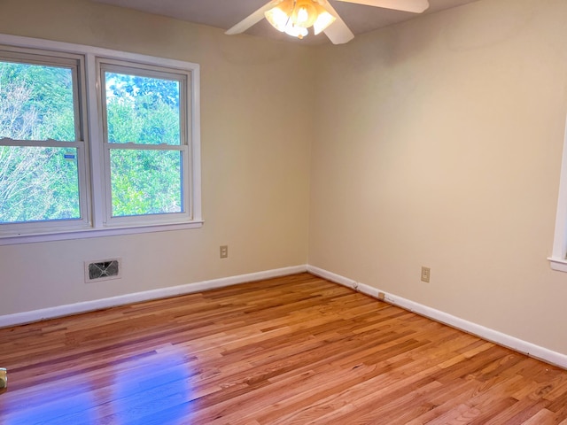 unfurnished room featuring light wood finished floors, baseboards, visible vents, and ceiling fan