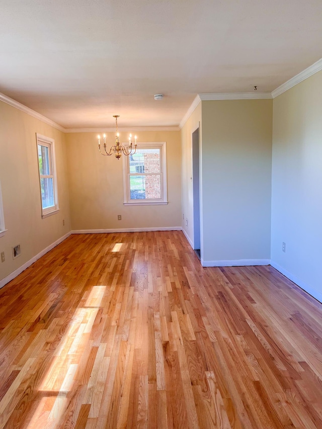 spare room with ornamental molding, light wood-type flooring, baseboards, and an inviting chandelier