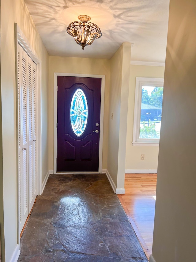 foyer featuring stone finish flooring, baseboards, and crown molding