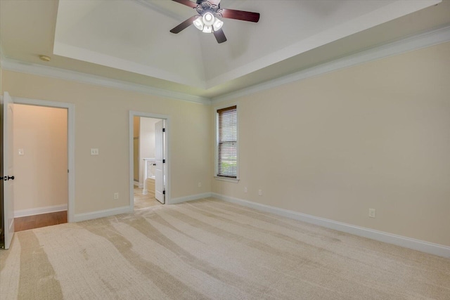 unfurnished room with ceiling fan, a raised ceiling, light colored carpet, and crown molding