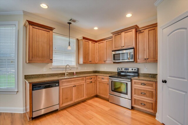 kitchen with sink, stainless steel appliances, pendant lighting, light wood-type flooring, and ornamental molding