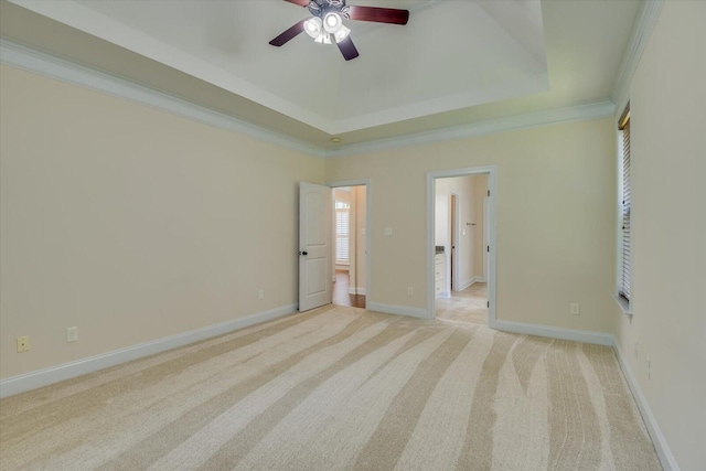 unfurnished bedroom featuring a tray ceiling, ceiling fan, light carpet, and ornamental molding