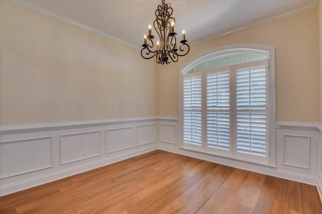 spare room featuring light hardwood / wood-style flooring, an inviting chandelier, a wealth of natural light, and ornamental molding