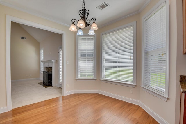 unfurnished dining area featuring a healthy amount of sunlight, light wood-type flooring, ornamental molding, and a notable chandelier