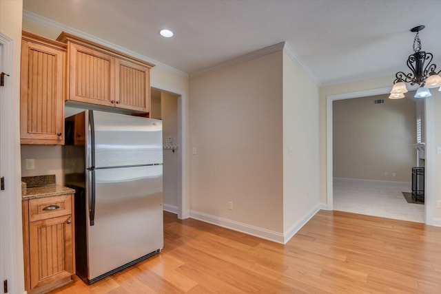 kitchen featuring pendant lighting, stainless steel fridge, ornamental molding, light hardwood / wood-style floors, and a chandelier