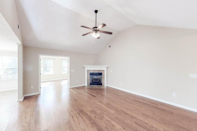 unfurnished living room with ceiling fan, light hardwood / wood-style floors, lofted ceiling, and a tile fireplace