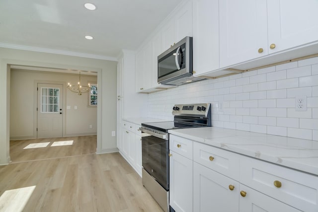 2319 Woodbine Rd, Augusta, GA 30904 - kitchen with appliances with stainless steel finishes, a chandelier, white cabinets, crown molding, and light wood finished floors