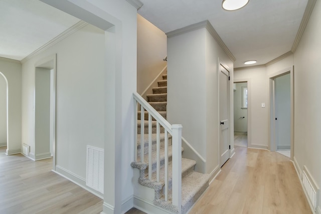 staircase with crown molding and wood-type flooring