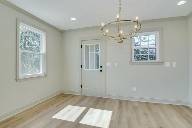 interior space with a healthy amount of sunlight, ornamental molding, a notable chandelier, and light wood-type flooring